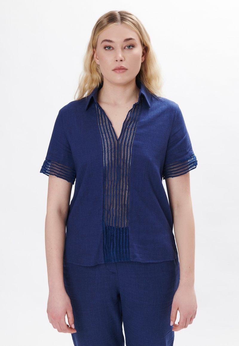 Camicia in lino blu navy a maniche corte con pannello in pizzo e colletto, caratterizzata da una profonda scollatura a V e maniche texturizzate.