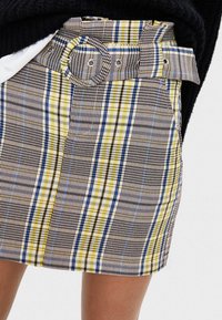 Károvaná miniskirt s páskem s kulatou přezkou v černé, žluté a modré barvě; skládá se z tkaniny s hladkou strukturou.