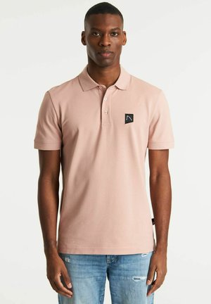 Polo shirt roz deschis din bumbac moale, cu guler cu două butoane, mâneci scurte și un patch cu logo negru pe partea stângă a pieptului. Purtați-l cu blugi bleu deschis.