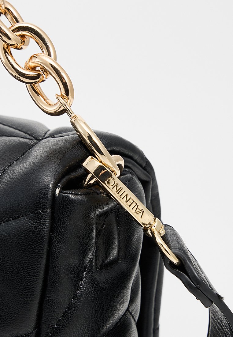 Zwarte leren handtas met een gequiltde textuur, voorzien van een gouden kettingband en een gouden sluiting gegraveerd met "Valentino."