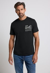 Camiseta de algodón negra con mangas cortas, que presenta un gráfico frontal en texto y líneas blancas; ajuste clásico, textura suave y diseño de cuello redondo.