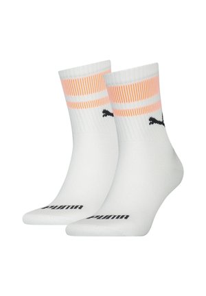 Calcetines deportivos blancos con rayas melocotón en la parte superior. Presentan el logo negro de Puma en el costado y una textura acanalada para mayor agarre.