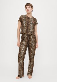 Set de pijamale cu imprimeu de leopard, dintr-un material moale; top scurt cu mâneci scurte și pantaloni largi cu talie elastică.