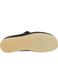 Musta sandaali, jossa on pehmeä, teksturoitu päällinen ja litteä, vaalean värinen kumipohja. Varustettu säädettävällä hihnalla turvalliseen istuvuuteen. Brändilogo näkyvissä.