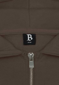 Hoodie zippé marron avec une fermeture éclair argentée et une étiquette indiquant "B large". Texture de tissu lisse et design simple.