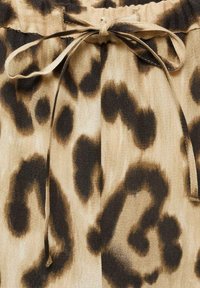 Leopard-patterned fabric with a beige and dark brown color scheme. Features a drawstring waist and soft, textured material.