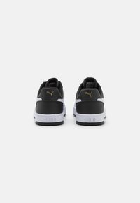 Black and white sneakers with a smooth leather upper, padded collar, gold logo on the heel, and textured rubber sole.