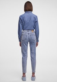 Jeansskjorta i medelblått, långärmad, med knäppning. Matchas med ljusblå, högmidjade jeans med bakfickor och ett märke.