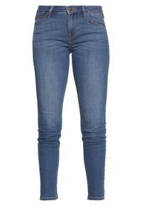 Jeans ajustados de tejido de mezclilla azul medio, con una cintura alta, diseño de cinco bolsillos y costuras de contraste. El dobladillo es ajustado en los tobillos.