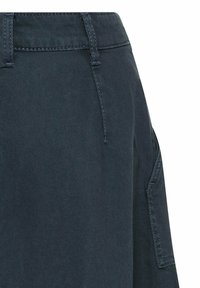 Donkerblauwe denim rok met een zichtbare tailleband, achterzak en stikseldetails, die een gestructureerde vorm en een gladde textuur benadrukt.