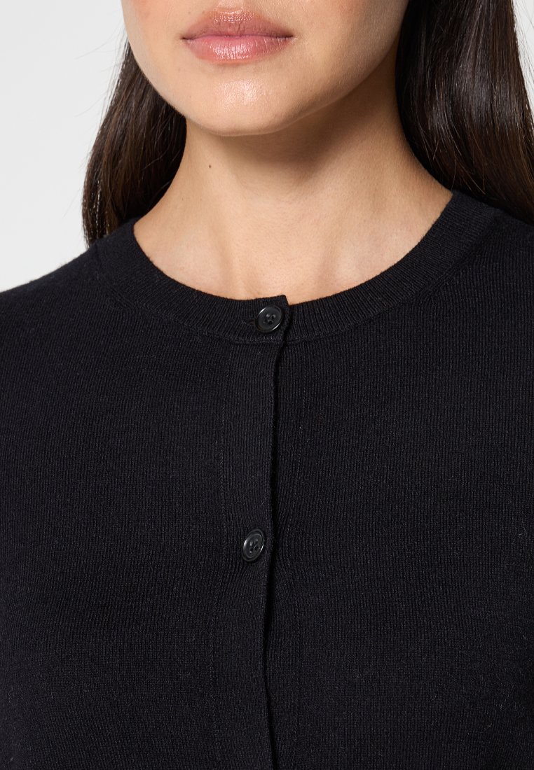 Czarny dzianinowy kardigan z okrągłym dekoltem, środkowym zapięciem na guziki oraz teksturalną tkaniną widoczną wokół guzików.