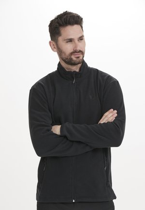 Zwarte fleece jas met een hoge kraag, ritsluiting en zijzakken. De stof lijkt zacht; heeft een subtiele logo op de borst.