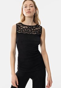 Black sleeveless top with a floral lace overlay at the neckline, featuring a fitted design and ribbed texture. Plain black fabric below the lace.