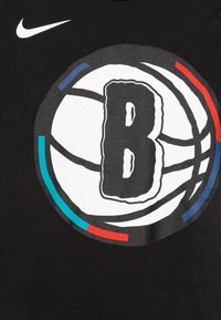 Svart bomull T-skjorte med en stor hvit basketballgrafikk med en fet bokstav "B" i sentrum; subtile fargede detaljer i blått og rødt.
