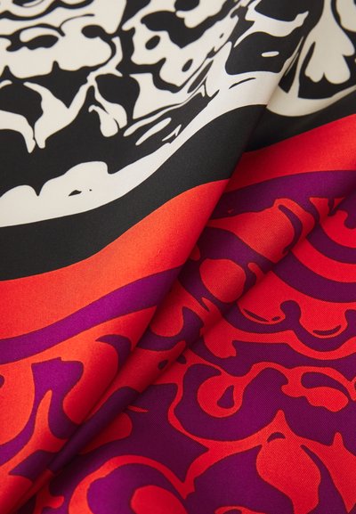 Silk scarf featuring a bold, abstract floral pattern in black, white, red, and purple. The smooth texture highlights the design's vivid colors.
