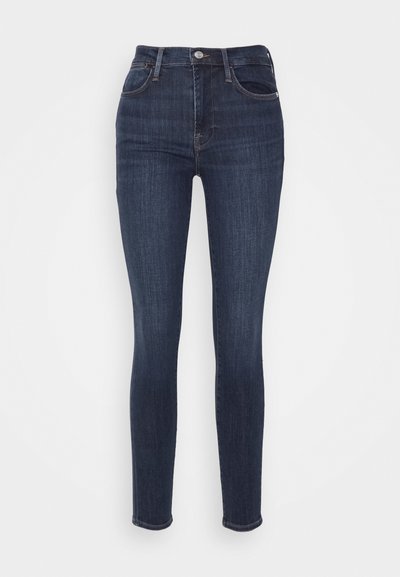 Jean skinny taille haute bleu marine en denim, avec un design à cinq poches, des coutures subtiles et une texture légèrement délavée.