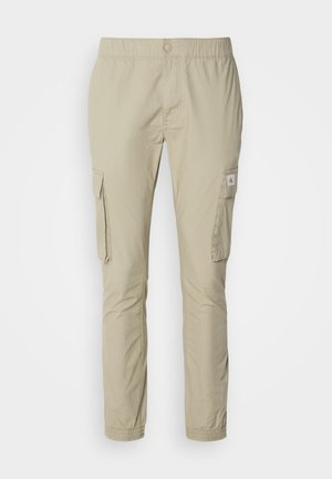 Beige cargo bukser med elastisk talje, to sidelommer og en glat tekstur. Funktioner et lille logo-patch på lommen.