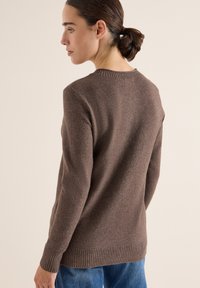 Brauner Strickpullover mit Rundhalsausschnitt, gerippten Bündchen und Saum, der eine weiche Textur und eine lockere Passform aufweist. Geeignet für die Freizeit.