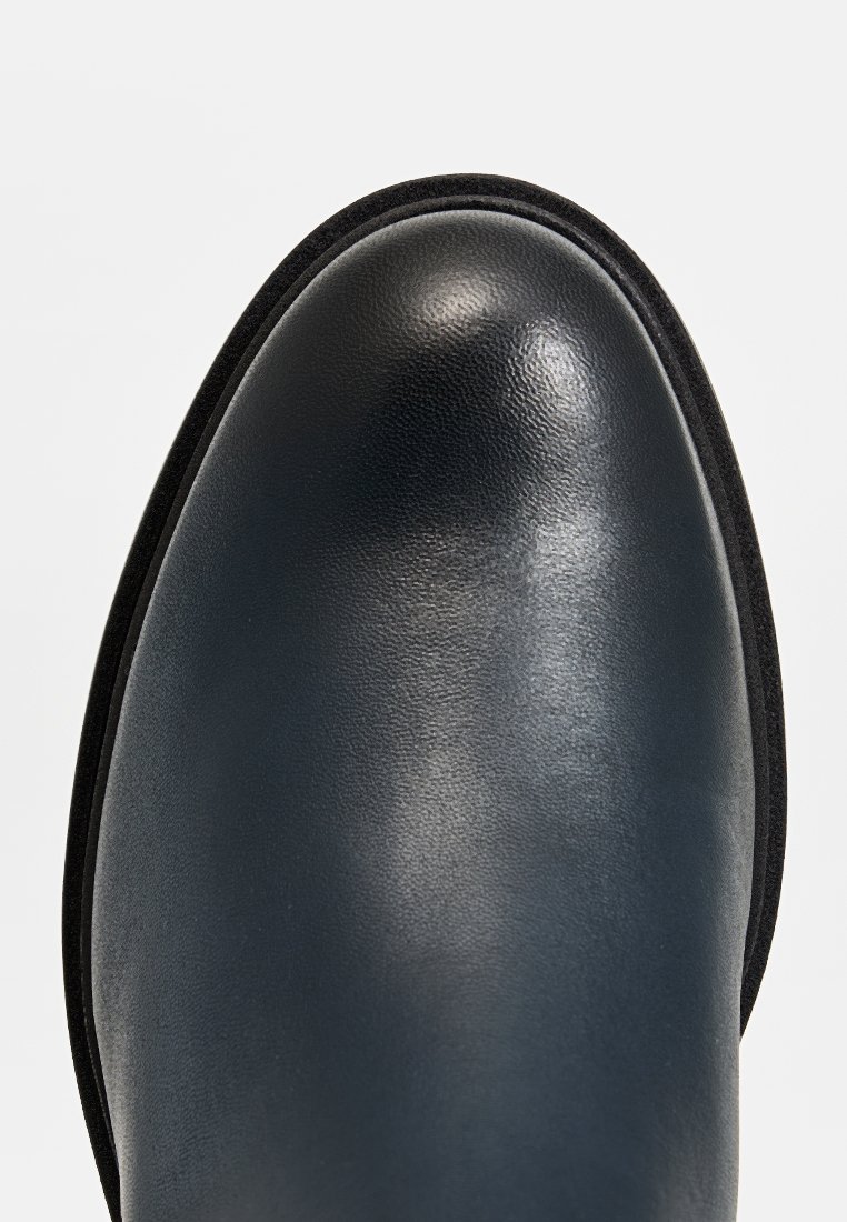 Stivale alla caviglia in pelle nera con finitura liscia, punta arrotondata e cuciture sottili. Presenta una suola in gomma nera a contrasto e un design elegante.