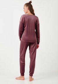 Mauve színű, belső velúr anyagú, hosszú ujjú pizsama szett, lazább szabással, kör alakú nyakkivágással és rugalmas mandzsettával a nadrágon, amely puha tapintású.