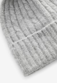 Szary, dzianinowy beanie wykonany z miękkiej, strukturalnej włóczki. Posiada żeberkowy wzór z subtelnymi splotami w formie kabli, co nadaje głębię i ciepło.