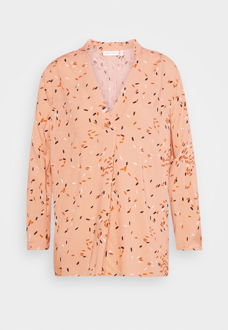 Světle broskvové tričko s dlouhým rukávem, výstřihem do V a rozptýlenými abstractními vzory v oranžové, černé a bílé barvě. Měkká tkanina s uvolněným střihem.
