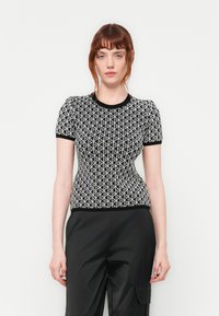 Zwart-wit top met korte mouwen en geometrisch patroon, voorzien van een ronde halslijn en een getailleerde pasvorm. Textuur gebreide stof.