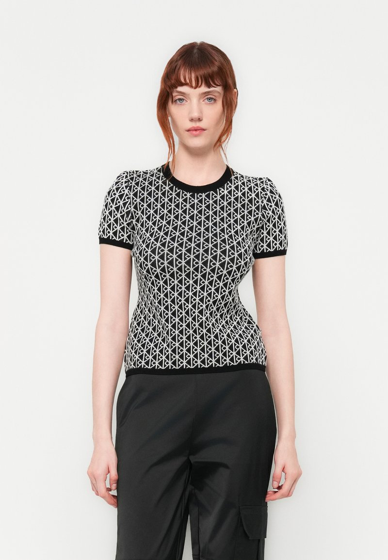 Zwart-wit top met korte mouwen en geometrisch patroon, voorzien van een ronde halslijn en een getailleerde pasvorm. Textuur gebreide stof.
