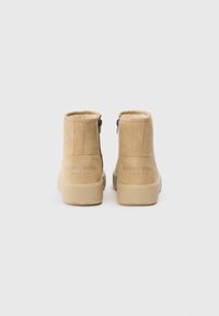 Bottines beige clair en suède lisse, avec des zips sur les côtés et une épaisse semelle en caoutchouc. Logo "Björg Borg" embossé sur le talon.
