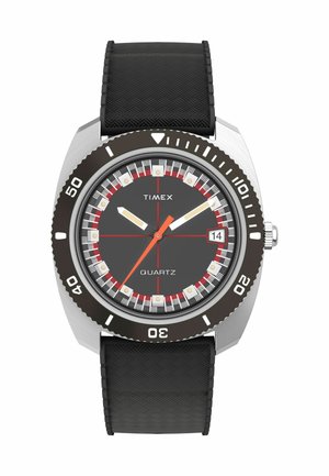 Montre quartz Timex avec un bracelet en caoutchouc noir, un boîtier en argent et un cadran gris foncé. Présente des accents rouges, des marqueurs luminescents et un affichage de la date.