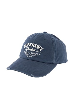 Casquette de baseball bleue avec le texte "Superdry Coastal Supply" brodé en blanc et de petits détails usés sur la visière.