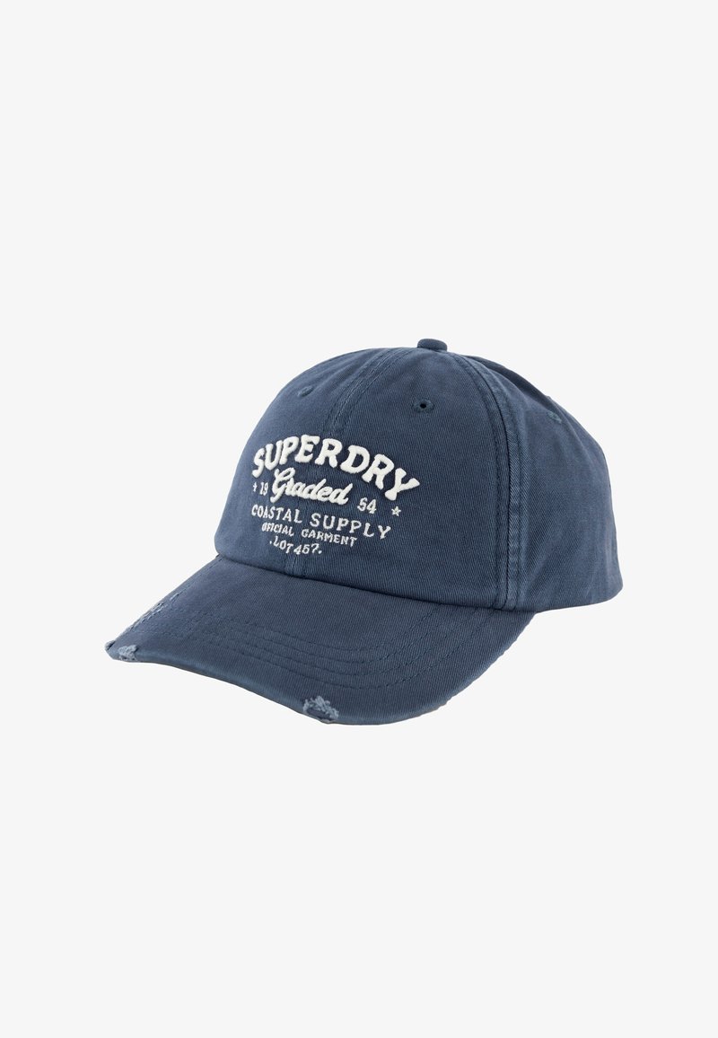 Casquette de baseball bleue avec le texte "Superdry Coastal Supply" brodé en blanc et de petits détails usés sur la visière.