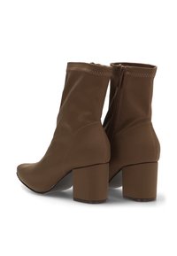 Botas de tobillo marrones hechas de material suave, con tacón cuadrado, cierre de cremallera y adornos cosidos a lo largo del borde superior.