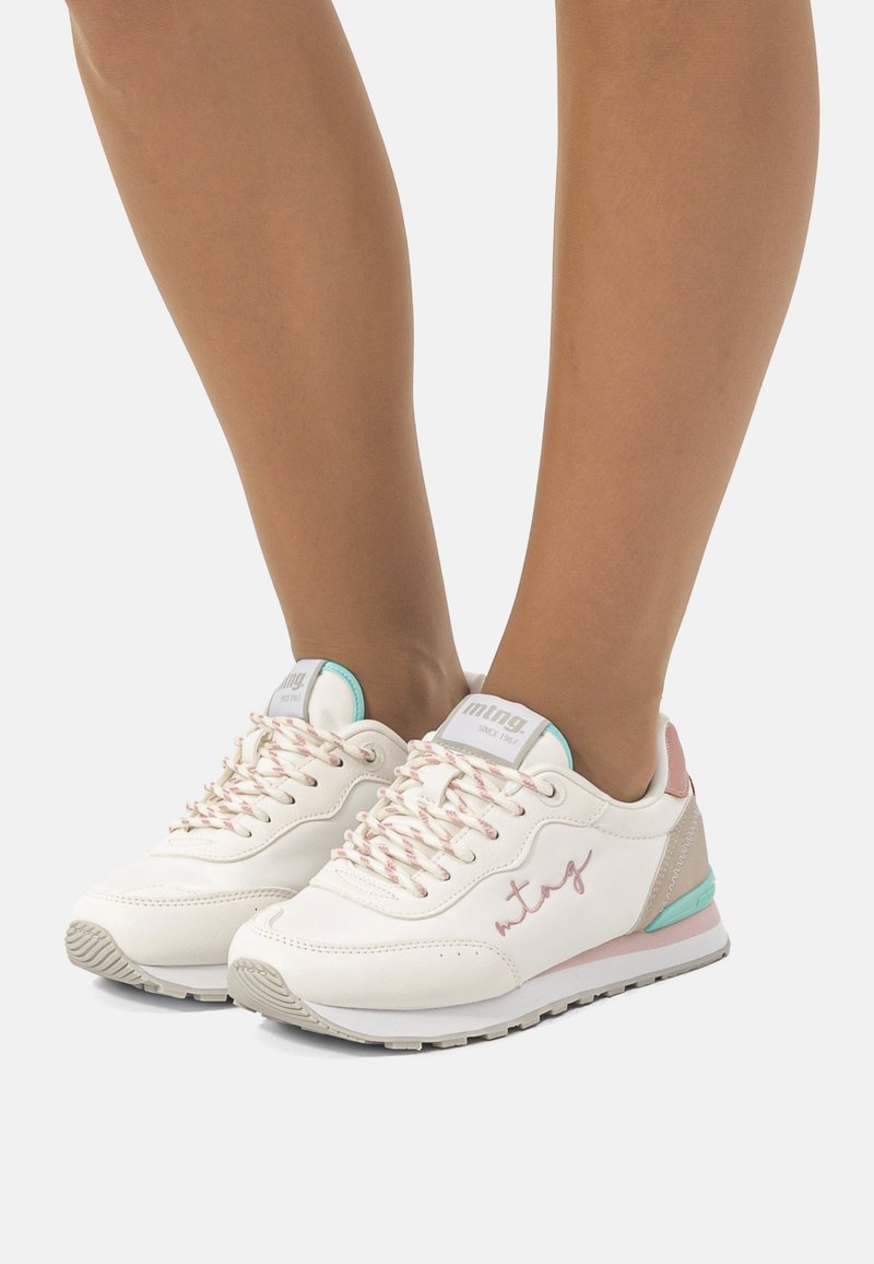 Zapatillas deportivas blancas con detalles en rosa, cuero texturizado, ribete azul pastel y cordones con estampado, que cuentan con un logo discreto en el costado.