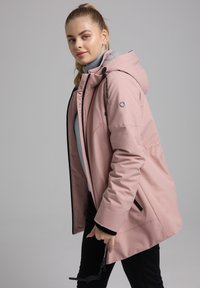 Roze waterdichte jas met capuchon, zwarte ritsaccenten, grijze binnenvoering en verstelbare trekkoorden. Bevat een logo op de mouw.