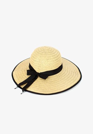 Laajen brimmoimien olkipäähine, jossa on kudottu rakenne, mustalla kankaisella nauhalla ja solmukkeella. Laitat on reunustettu mustalla trimmi.