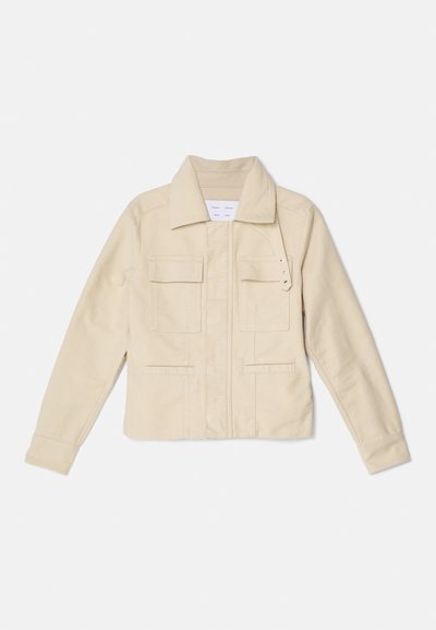 Vaaleanbeige canvas-takki, jossa on kaulus, etuvetoketju, kaksi rintataskua ja sivuhalkiot. Varustettu koristeellisilla napeilla ja rakenteellisella istuvuudella.