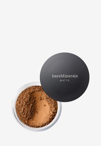 Polvo mineral suelto mate en un recipiente transparente con tapa negra. El polvo es de color marrón claro y tiene una textura suave y fina.