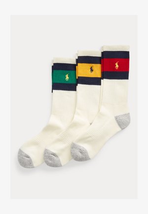 Tre hvite crew-sokker med grå tupper, hver med en marineblå stripe og en fargeblokk i grønt, gult eller rødt med en brodert polo-spillerlogo.