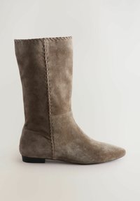 Suede ankle boot in taupe with a pointed toe, subtle stitching detail along the seam, and a flat black sole.