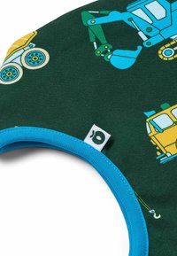 Tessuto verde con stampe di veicoli da costruzione in blu e giallo. Una rifinitura blu circonda il collo. Etichetta visibile sul bordo.
