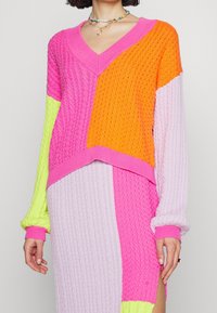 Sukienka sweterkowa z dzianiny, z dekoltem w serek, w żywych kolorach, takich jak różowy, pomarańczowy i limonkowy, z fakturowanymi wzorami i ściągaczami na mankietach.