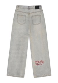 Jean large gris clair vu de dos avec deux poches et texte rouge "Don Ed Hardy designs" sur la jambe droite près de l'ourlet.