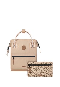 Sac à dos beige avec une texture lisse, doté d'une poche zippée à l'avant et d'une poignée contrastante. Accompagné d'une trousse assortie en imprimé léopard.