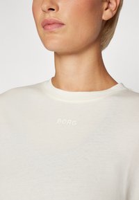 Lys kremfarget sweatshirt med rund hals og subtil "BORG" logo i lys tekst på brystet. Myk, glatt stoffkvalitet.