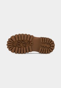 Καφέ σόλα λαστιχένινης μπότες με βαθιές εγκοπές, με τη λέξη "BUFFALO" και ένα κυκλικό λογότυπο κοντά στη φτέρνα πάνω σε λευκό φόντο.