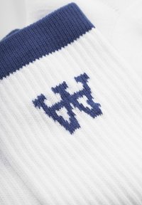 Calcetines blancos de punto con una textura acanalada, con un puño azul marino y un diseño de logo azul marino en la parte frontal. Material de algodón suave.