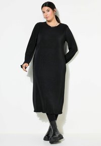 Zwarte geribbelde maxi-jurk met lange mouwen, ronde halslijn en textuurstof. Gestyled met chunky zwarte enkelboots.