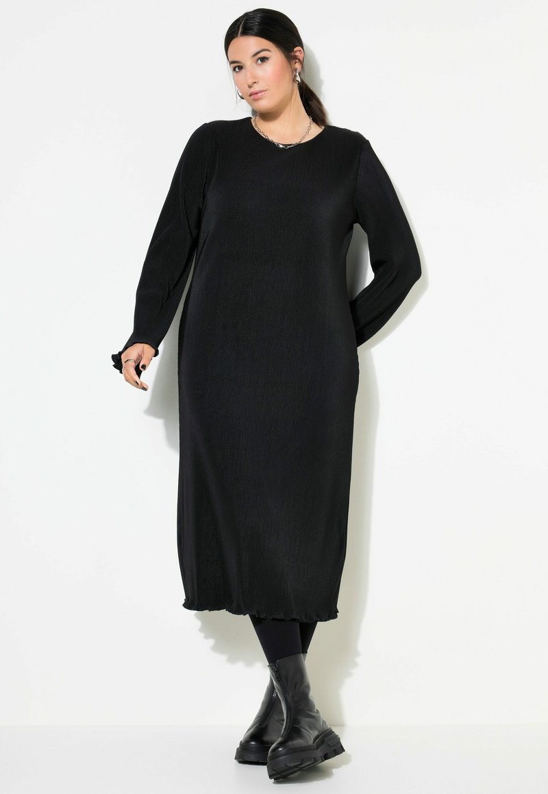 Zwarte geribbelde maxi-jurk met lange mouwen, ronde halslijn en textuurstof. Gestyled met chunky zwarte enkelboots.
