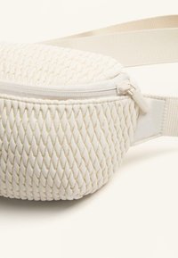 Borsa a spalla bianca intrecciata con superficie testurizzata, dotata di chiusura con zip, tracolla regolabile e retro in tessuto liscio.
